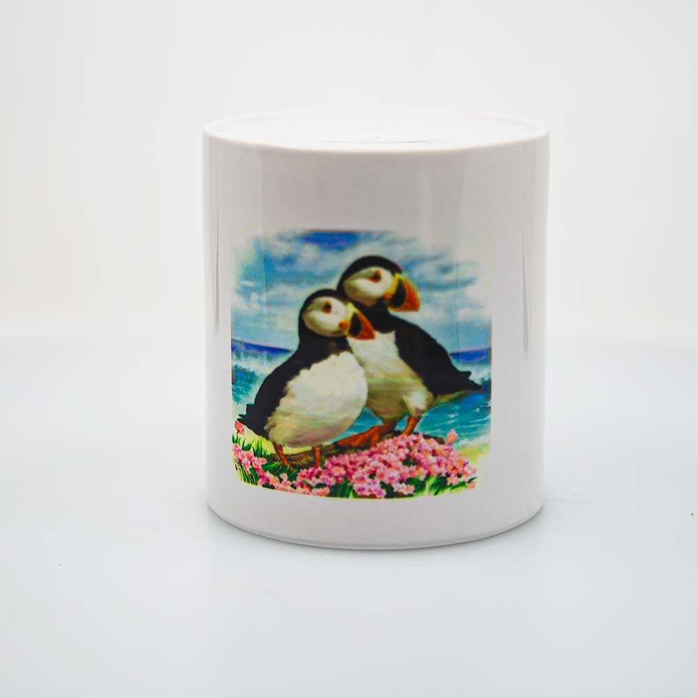 An image of a pair of puffins look off into the distance on this round, ceramic piggy bank or money jar.