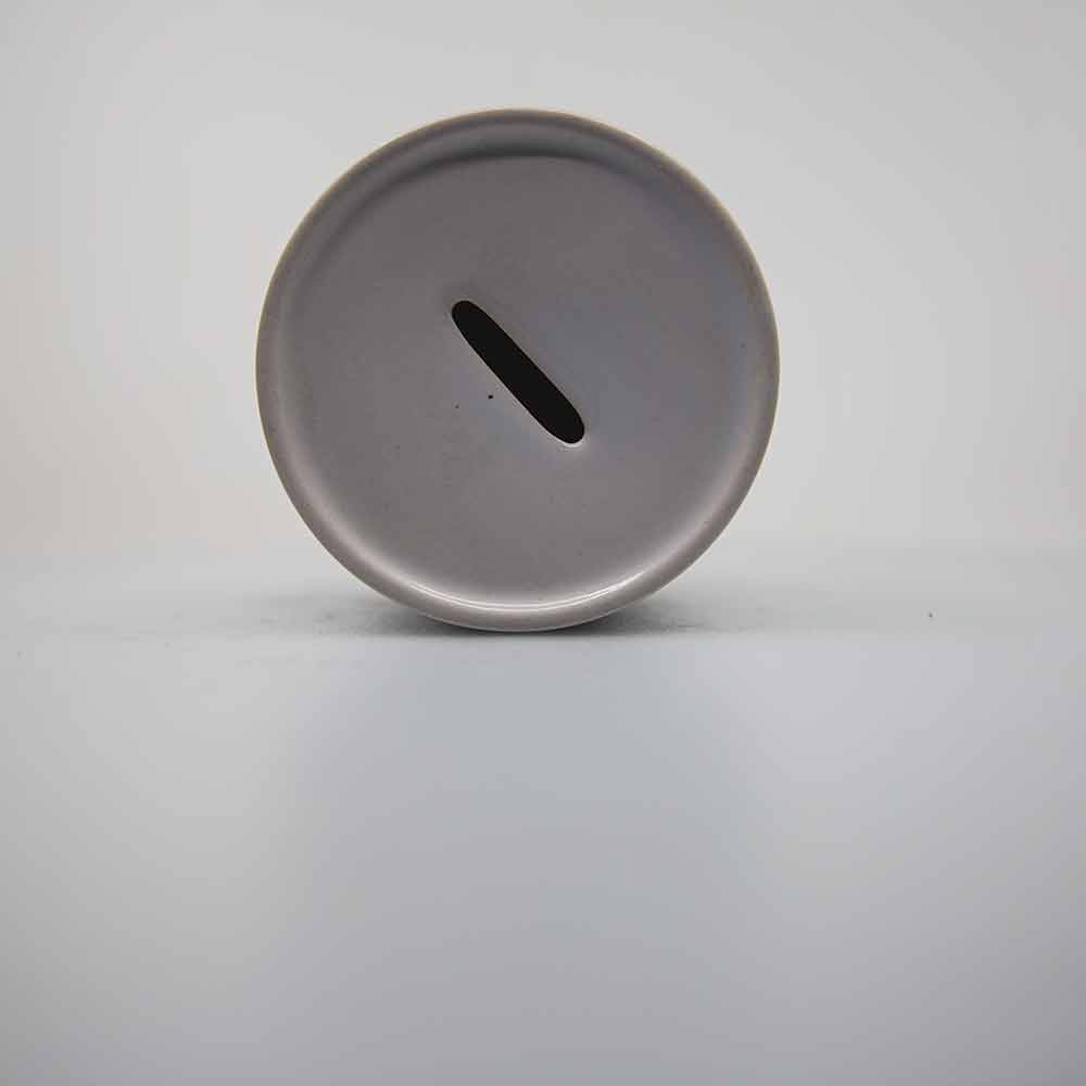 The round ceramic "piggy bank" or money jar top showing the slot that the coins or bills slip into.