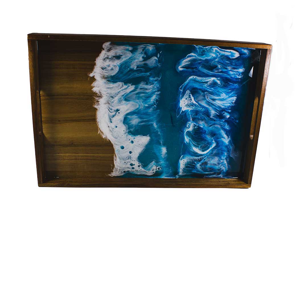 A wood serving tray with a resin ocean themed painting on a white background.